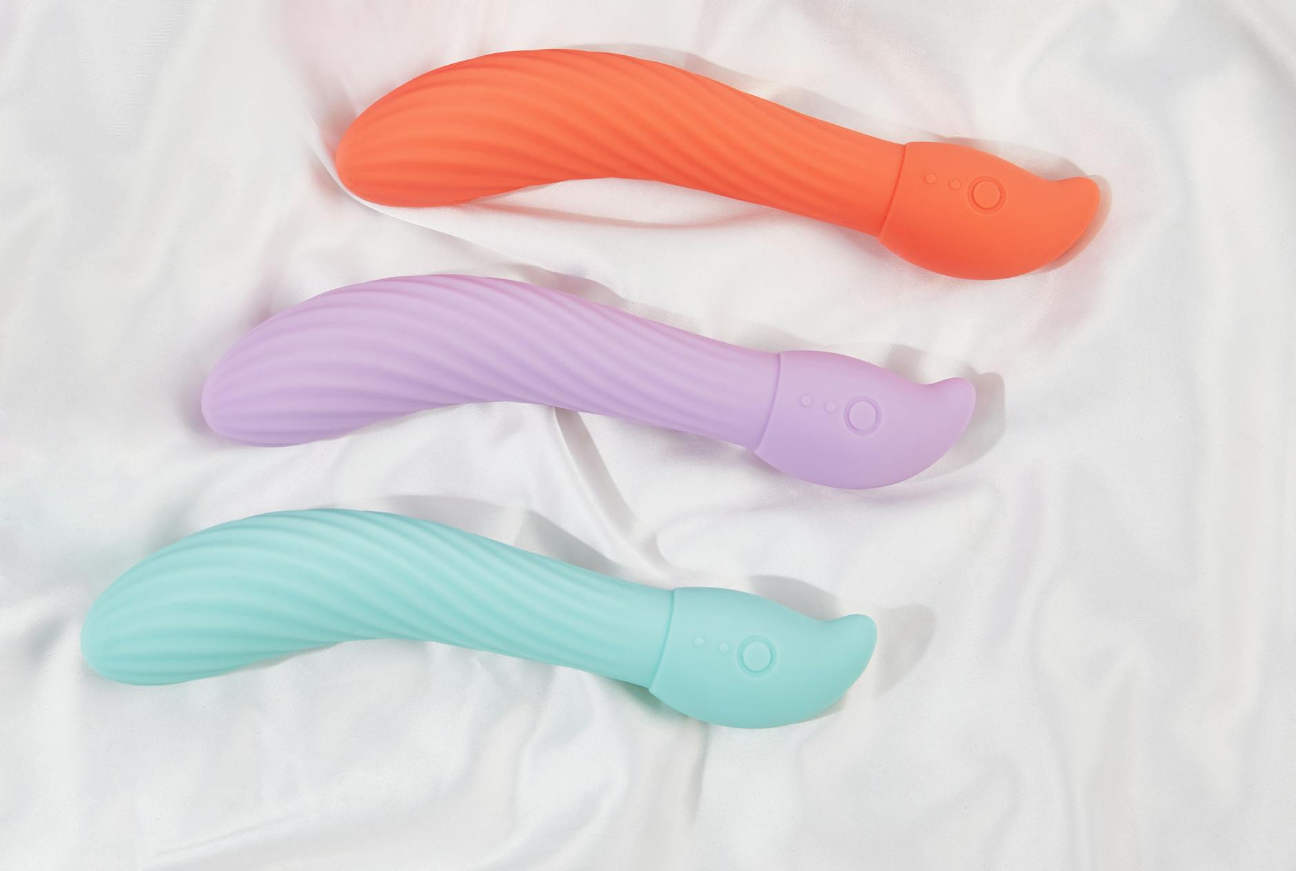 A hand holding an orange vibrator against a minimalistic purple backdrop, showcasing gentle sensuality