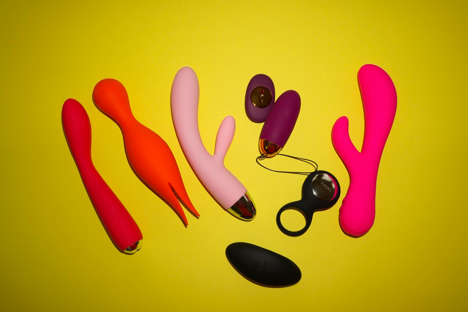 Colorful vibrators and intimate wellness toys displayed on a bright, modern yellow background
