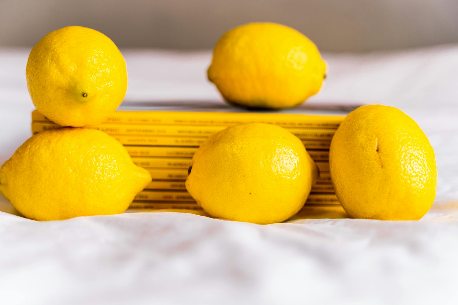 Fresh lemons and stacked books on white surface, symbolizing knowledge and aging with pleasure